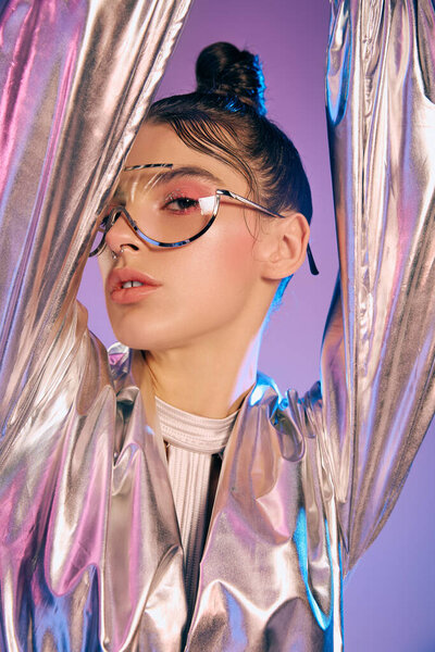 A young woman dressed in metallic futuristic attire poses confidently against a colorful backdrop