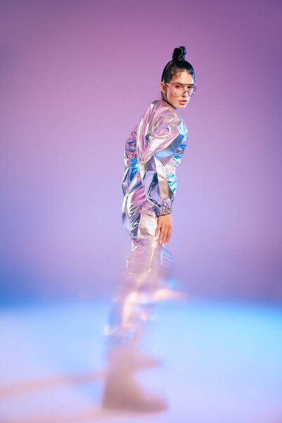 Стильная женщина выставляет напоказ свой голографический наряд на ярком фоне, излучая элегантность.