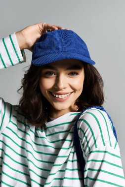 Genç bir kadın şık çizgili bir bluz ve mavi bir şapka giyer, ışıl ışıl yaz neşesi ve tarzı.