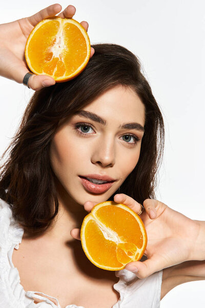 A young woman holds fresh oranges, radiating joy and style on a sunny summer day.