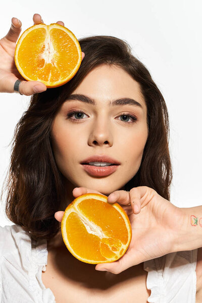 A stylish young woman in summer fashion holds bright orange fruit, radiating joy.