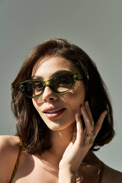 Молодая женщина спортивно выглядит летом, в комплекте со стильными солнцезащитными очками и уверенностью.