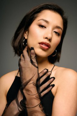 Genç bir kadın şık siyah eldivenleri ve büyüleyici makyajıyla eşsiz moda anlayışını sergiliyor..