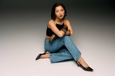 Genç bir kadın şık giyinmiş, şık giyinmiş, ışıl ışıl bir güzellikle otururken kendine güvenir..