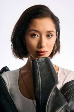 Kendine güveni tam bir kadın deri ceketiyle poz verirken moda saç stilini ve ifadesini sergiliyor..