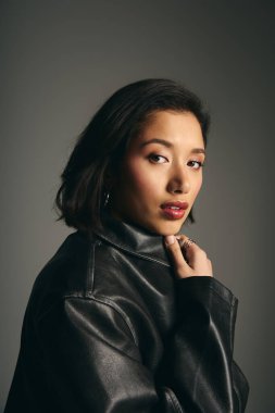 Kendine güvenen genç bir kadın şık tarzını yumuşak ışıklı yaratıcı bir stüdyoda sergiliyor..