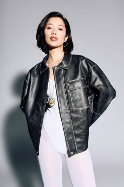 Tarz sahibi genç bir kadın, modaya uygun siyah ceketi ve eşsiz modayla kendinden emin bir şekilde ayakta duruyor..