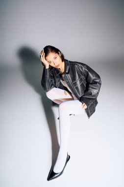 Şık genç bir kadın zarif bir şekilde oturur, kendine güveni ve çağdaş yeteneği yayar..