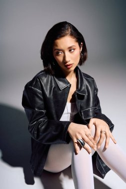 İleri moda genç bayan zarif bir şekilde oturuyor, modern bir ortamda eşsiz tarzını sergiliyor..