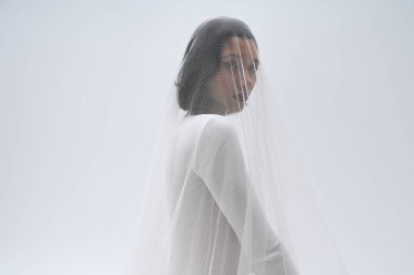 Güzel genç bir gelin zarif pozlar verir, duvağıyla süslenir, neşe ve zarafet saçar..