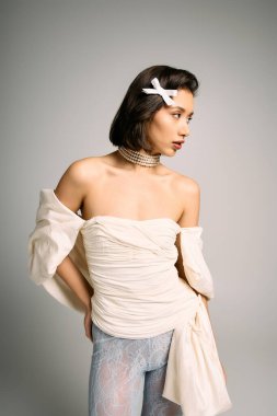 Genç gelin zarif bir şekilde poz veriyor, zarif bir elbise içinde zarif aksesuarlar takıyor, neşe saçıyor..