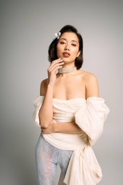 Güzel, genç bir gelin zarif bir şekilde, modern bir gelinliğe güvenerek poz verir..