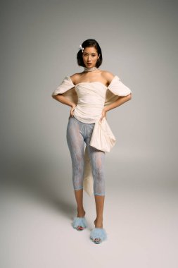 Moda ve modern kıyafetlerle kendine güvenen genç bir gelin minimalist bir arkaplanda duruyor..