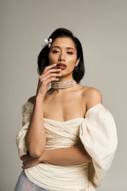 Genç bir gelin kendine güveni tam bir gelinlik içinde duruyor. Bu gelinlik onun zarif özelliklerini ön plana çıkarıyor..