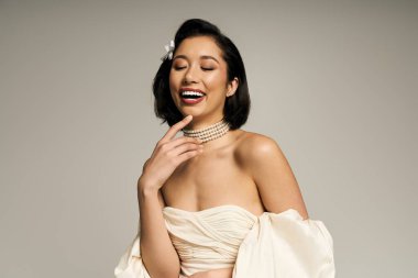 Genç bir gelin, zarif bir elbiseyle güzelliğini ve zarafetini sergileyerek mutlulukla ışıldıyor..