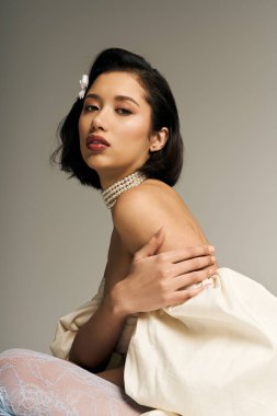 Güzel, genç bir gelin zarif bir şekilde poz verir, cazibesini göstererek, sakin bir ortamda.