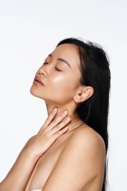 Genç bir kadın zarifçe poz verir, doğal güzelliğini minimalist bir ortamda ön plana çıkarır..