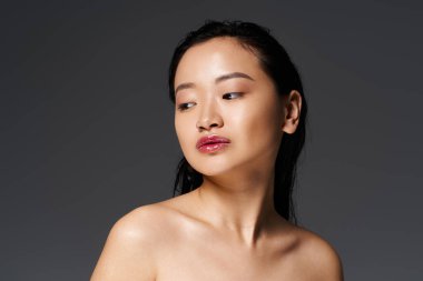 Genç Asyalı bir kadın zarifçe poz verir, doğal güzelliğini ve çekiciliğini ön plana çıkarır..