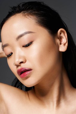 Genç Asyalı bir kadın doğal güzelliğini bir stüdyo ortamında sergiliyor, özgüven ve zarafet saçıyor..