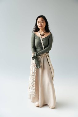 Genç bir Asyalı kadın kendine güvenir uzun bir etek giyer ve üstünü giyer, tarzını gösterir..