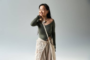 Parlak gülümsemeler odayı aydınlatırken Asyalı genç bir kadın zarif ve şık bir kıyafet modelliyor..