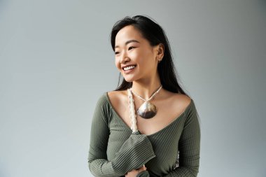 Parlak ve neşeli genç Asyalı kadın çarpıcı bir kolye tasarımı sergilerken güzellik saçıyor..