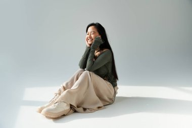 Parlak doğal ışık, yerde oturan neşeli genç bir kadını vurgular..