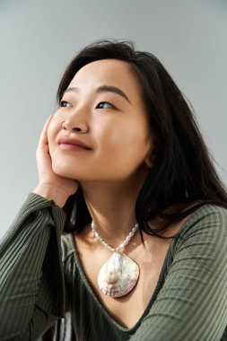 Genç bir kadın nazikçe bakıyor, çenesi elinde, zarafet saçıyor..