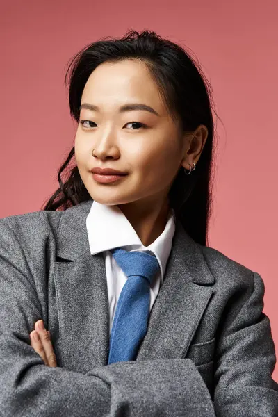 Genç Asyalı bir kadının büyüleyici portresi. Kollarını kavuşturmuş, gülümsüyor..