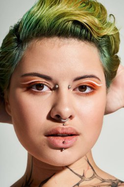 Şık bir ortamda şık bir kadın yaratıcı makyaj ve canlı saç rengiyle kendine güvenerek poz verir.