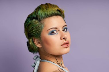 Kendine güvenen yeşil saçlı ve sanatsal makyajlı genç bir kadın stil yayar..
