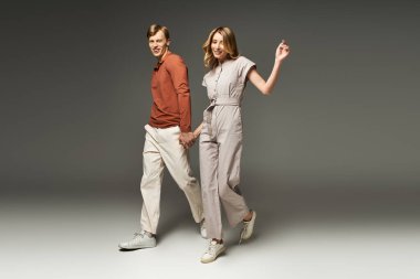 Genç bir çift modern bahar modasını sergiliyor, el ele, stüdyoda neşe ve tarz yayıyorlar..