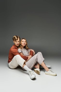 Havalı bahar kıyafetleri içinde genç bir çift stüdyoda poz veriyor, şık bir çekiciliği var..