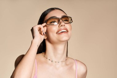 Genç bir kadın son moda güneş gözlüğü takıyor, parlak bir gülümseme ve yaz bronzlaşması sergiliyor..