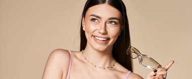 Genç kadın, son moda güneş gözlüklerini ve ışıl ışıl gülüşünü sergilerken yaz güneşinin tadını çıkarıyor.