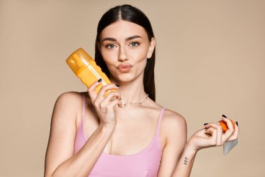 Genç bir kadın güneşlenmek için neşeyle güneş kremi tutarken yazdan zevk alır..