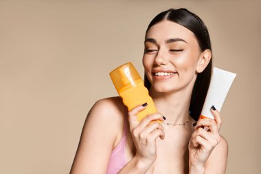 Neşeli genç bir kadın güneş yanığı ve cilt bakımı için gerekli olan yaz malzemelerini sergiliyor..