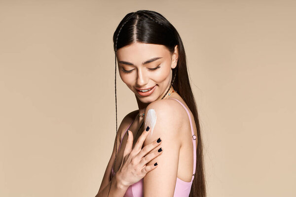 Красивая молодая женщина наносит солнцезащитный крем на плечо, светящийся загаром.