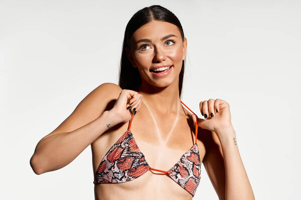 Молодая женщина наслаждается солнечным днем, демонстрируя свой прекрасный загар и игривый дух.