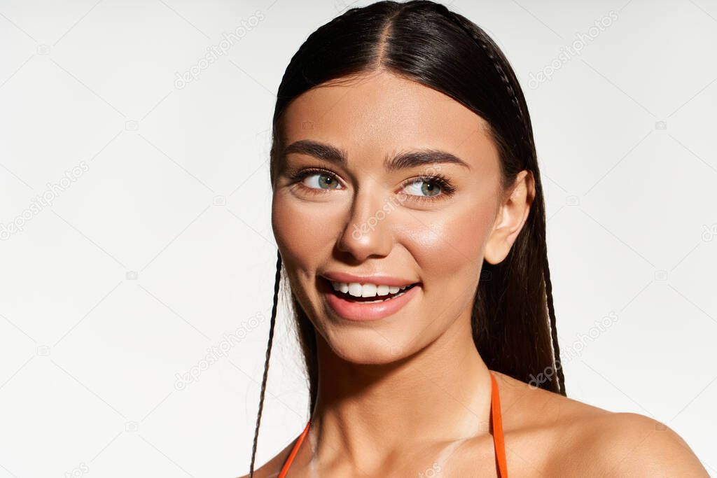 A young woman enjoys the sunshine, showcasing her radiant tan and summer vibes.