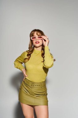 Genç bir kadın şık bir kıyafet ve şık bir güneş gözlüğü takıyor..