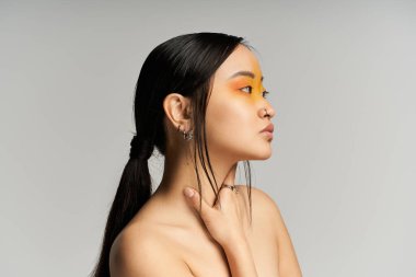 Canlı makyajlı genç bir Asyalı kadın yaratıcı bir stüdyoda düşünceli bir şekilde poz veriyor..