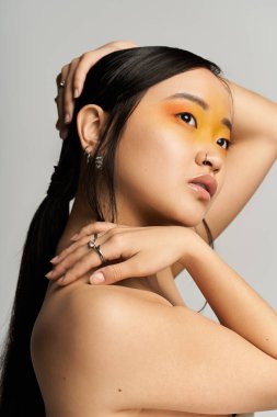 Genç ve güzel bir Asyalı kadın zarif pozlar veriyor sarı göz makyajıyla, kendinden emin..