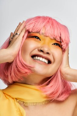 Pembe saçlı, cesur makyajlı neşeli bir Asyalı kadın gururla hayat dolu tarzını sergiliyor..