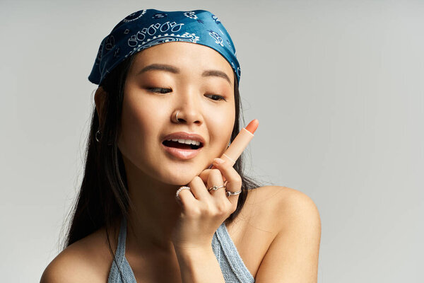 Intriguing young woman with a bandana playfully poses while contemplating her next creative idea.