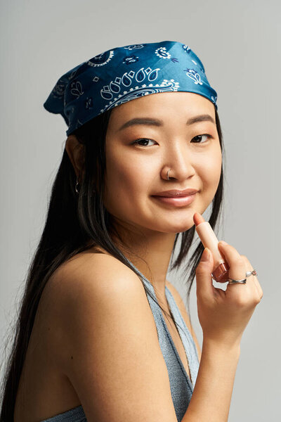 A young Asian woman smiles as she showcases her makeup skills in a modern studio.