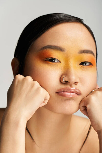 A young Asian woman poses thoughtfully with vibrant makeup that showcases her creativity.