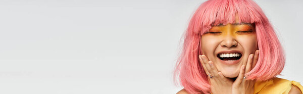 Молодая азиатская женщина с яркими розовыми лучами волос от счастья, демонстрируя свою сияющую улыбку.