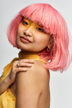 Genç bir Asyalı kadın kendine güvenerek çarpıcı pembe saçlarını ve kalın makyajını sergiliyor..