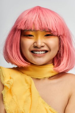 Genç ve güzel bir Asyalı kadın parlak pembe saçları ve kalın makyajıyla neşeli tarzını sergiliyor..